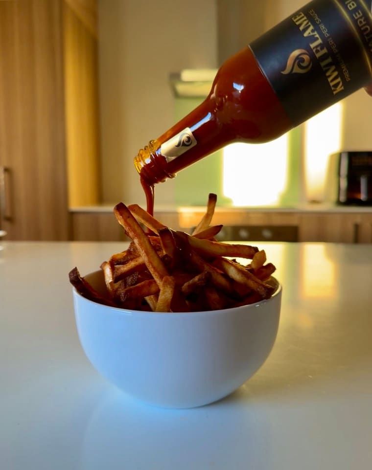 Kiwi Flame being poured over a bowl of hot chips